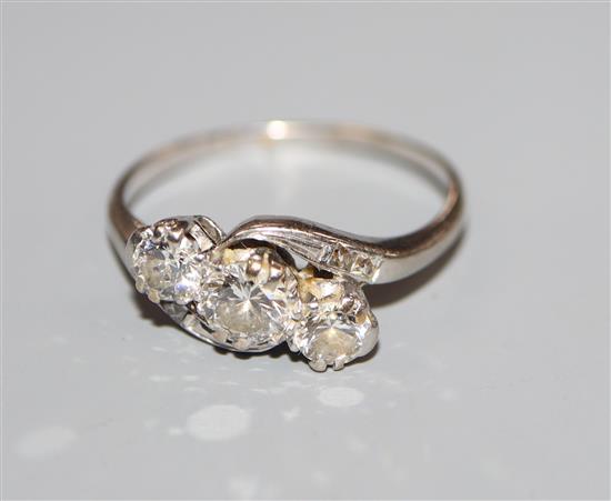 A mid 20th century white metal and three stone diamond crossover ring, size 0/P.